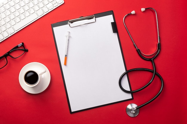 Photo stethoscope in doctors desk with tablet and coffee cup, top view