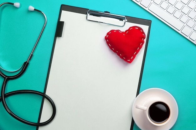 Stethoscope in doctors desk with tablet heart and coffee cup top view