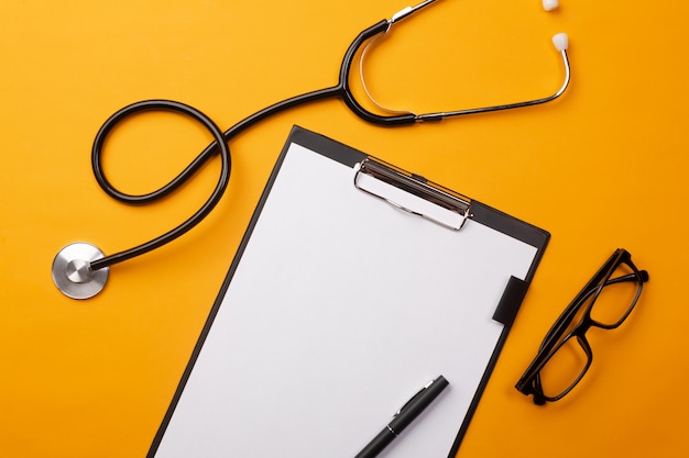 Stethoscope in doctors desk with tablet, pen and pills