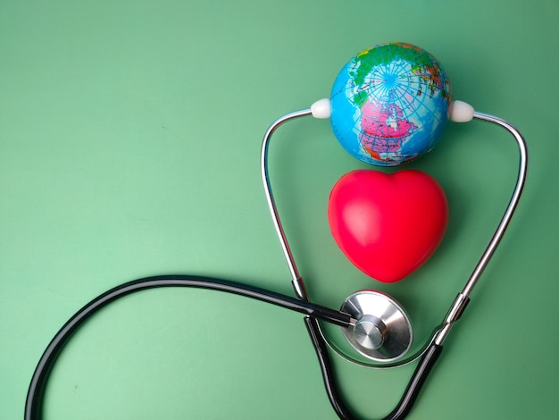 Stethoscope, earth globe, and red heart on a green background