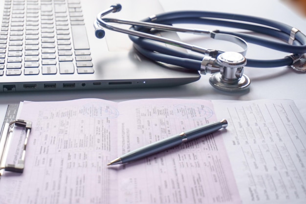 Stethoscope glasses and a pen with documents lie near the laptop