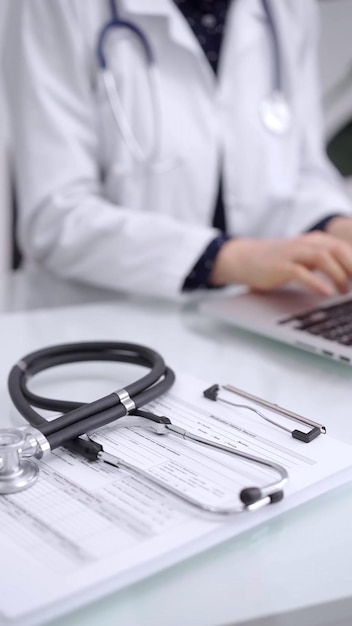 Photo stethoscope is lying on the glass table while doctor woman is working with laptop computer on the background closeup medicine and pharmacy concept