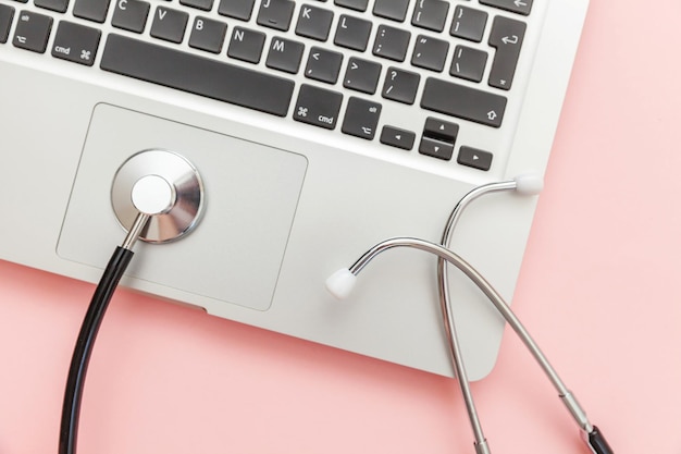 Stethoscope keyboard laptop computer isolated on pink background Modern medical Information technology and sofware advances concept Computer and gadget diagnostics and repair