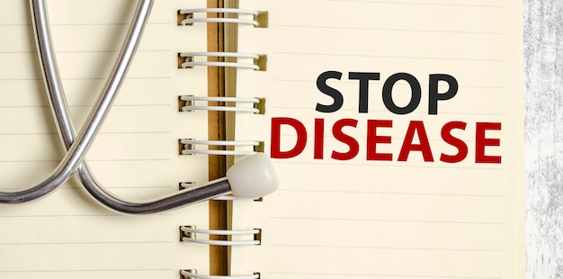 Stethoscope and notebook with stop disease text on notebook