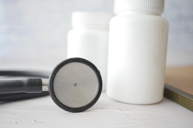 Stethoscope and pills container on wooden background