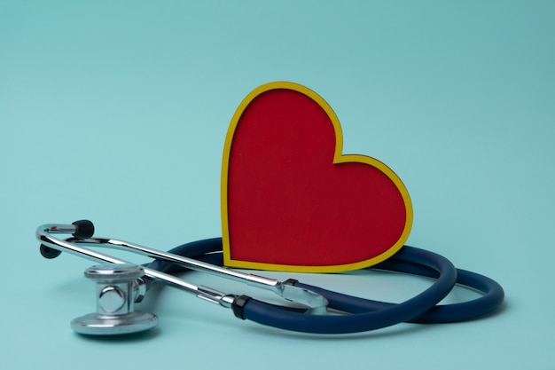 A stethoscope and a red heart on a blue background. The concept of cardiology.