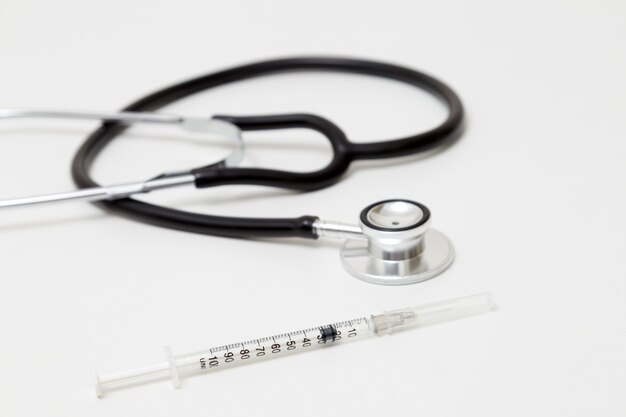 Photo stethoscope and syringe on table. isolated on white background. studio lighting. concept for healthy and medical