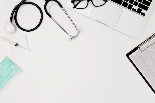 Stethoscope, Top view of doctor's desk table, blank paper on white background, above view doctor work tools on white, Stethoscope, laptop, eyeglass and medical drug on white background, medical doctor