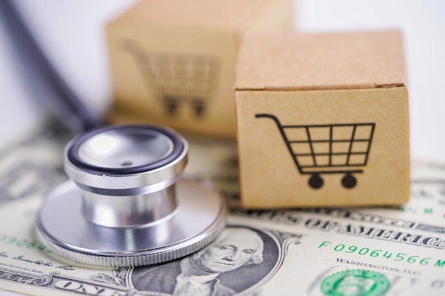 Stethoscope on US dollar banknotes with shopping cart box.