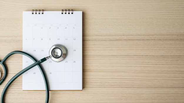 Stethoscope with calendar page date on wood table background doctor appointment medical concept