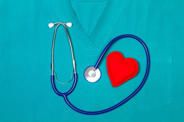 A stethoscope with a fabric red heart on a green medical uniform in a top view