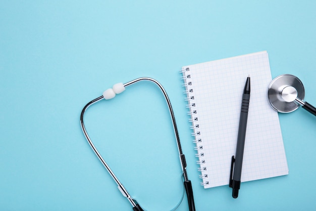 Photo stethoscope with notebook on blue