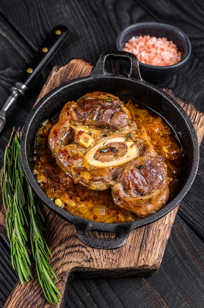 Stew veal shank meat OssoBuco,  italian osso buco steak. Black wooden background. Top view.