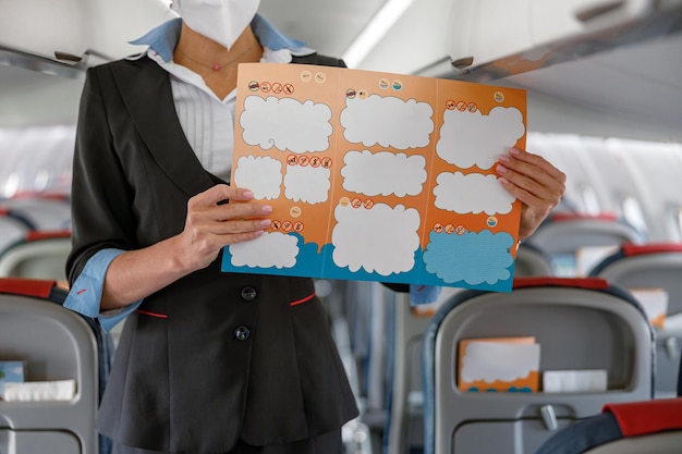 Stewardess with paper booklet standing in aircraft passenger salon