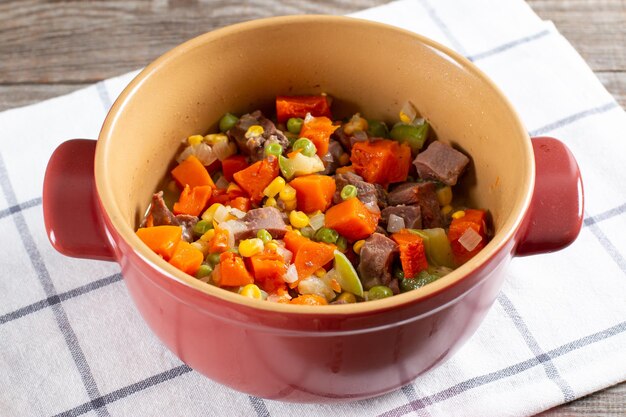 Stewed beef tongue with vegetables close-up in a saucepan on the table. horizontal