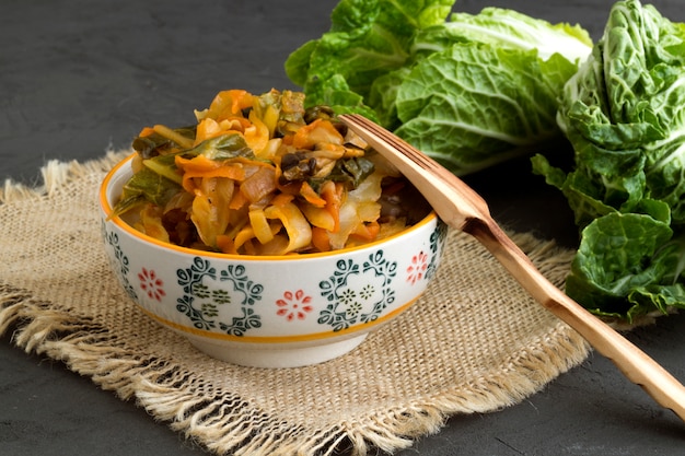 Stewed cabbage in bowl on grey background.