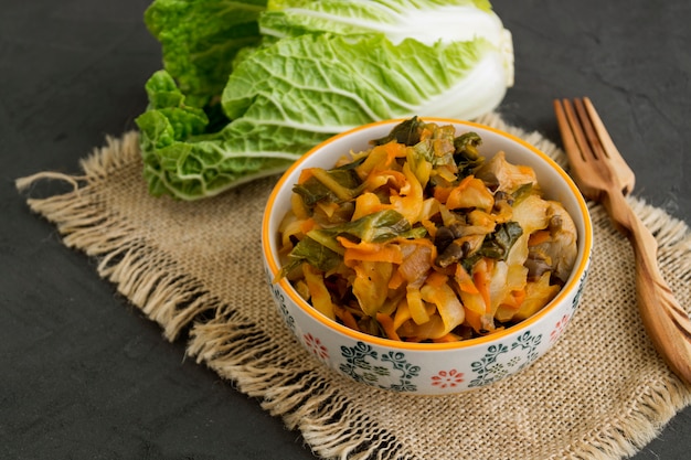 Stewed cabbage in bowl on grey background.