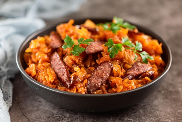 Stewed cabbage with sausages in black plate horizontal view from