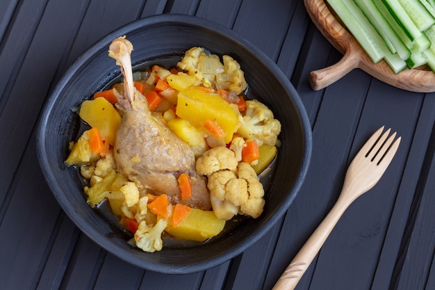 Stewed duck with vegetables in a black clay bowl