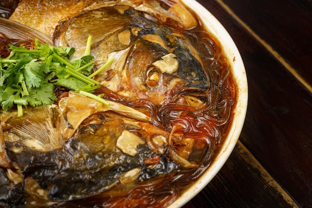 Stewed fish head with vermicelli a special dish of Northeast China on a wooden background