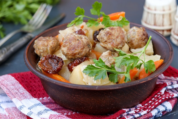 Photo stewed potatoes with meatballs, carrots and sun-dried tomatoes in a bowl