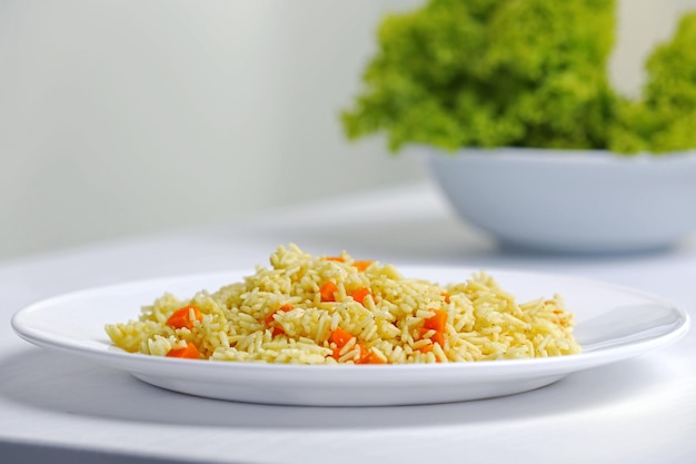 Stewed rice with a carrot on a white plate