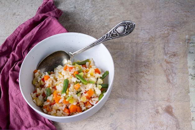 Stewed rice with vegetables, vintage spoon, red napkin, copy space