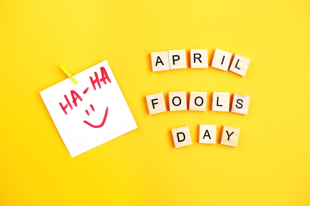 Sticker with smiley and inscription april fools day made by wooden cubes on yellow background