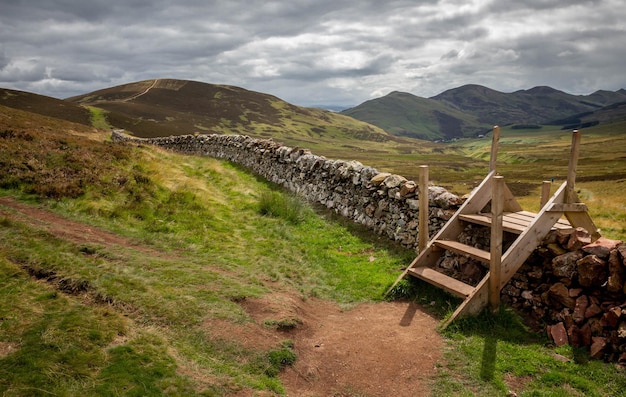 Stile with wooden steps over a stone wall in the pentland hills in Edinburgh