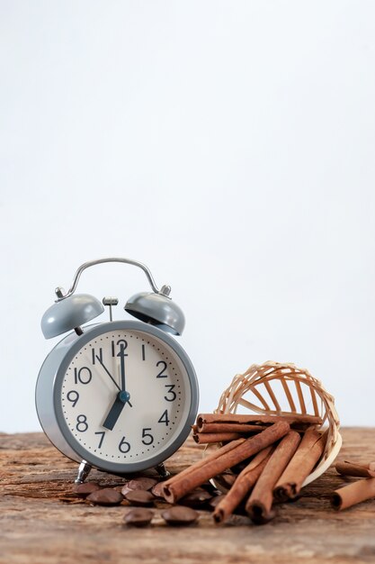 Still life of alarm clock and cinnamon stick on old wooden