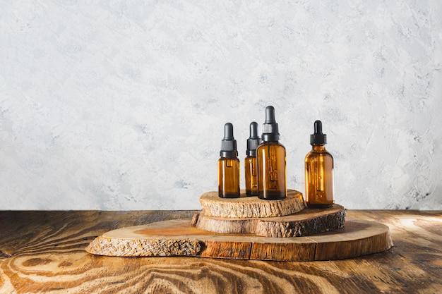 Still life of bottles of essential oils on driftwood on a gray textured background