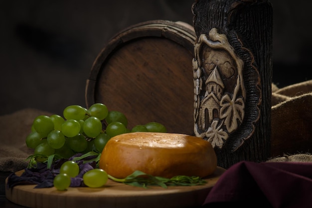 Still life of cheese wine bottle and grapes on a background