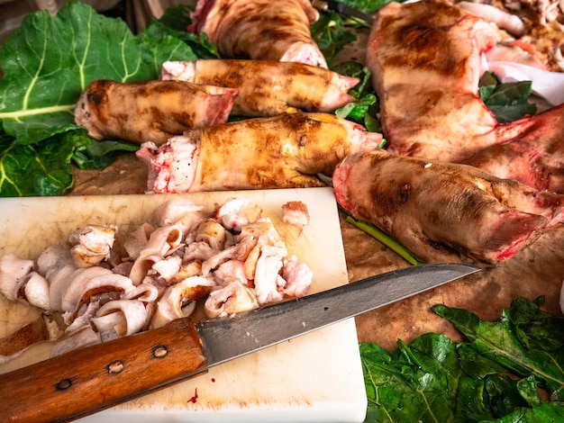 Still life consisting of some pig39s trotters on cabbage leaves and a table with cut pork meat and a large knife