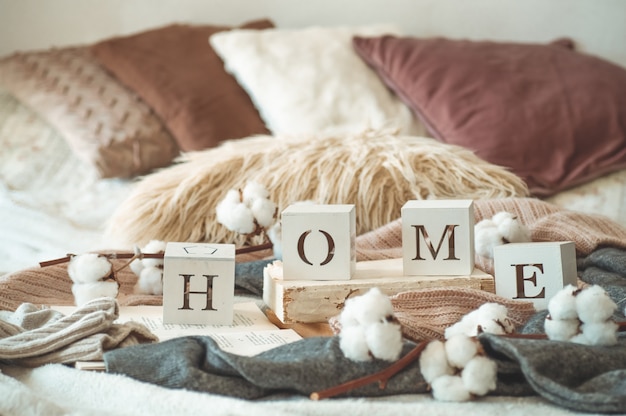 Still life details in home interior of living room and the inscription HOME. Books and cup of tea with cone and cotton. Read, Rest. Cozy autumn or winter concept, knitwear. Cozy autumn winter concept