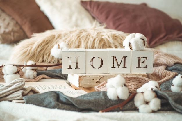 Still life details in home interior of living room and the inscription HOME. Books and cup of tea with cone and cotton. Read, Rest. Cozy autumn or winter concept, knitwear. Cozy autumn winter concept