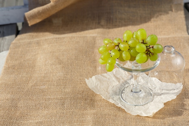 Still life and food photo A dish with a bunch of grapes stands on a burlap