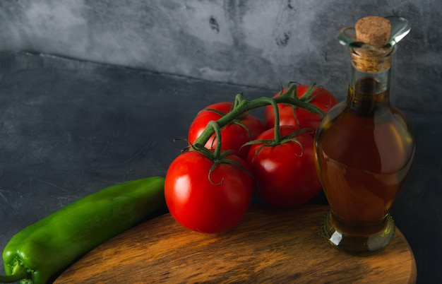 Still life food with olive oil green peppers and ripe tomatoes in dark scene