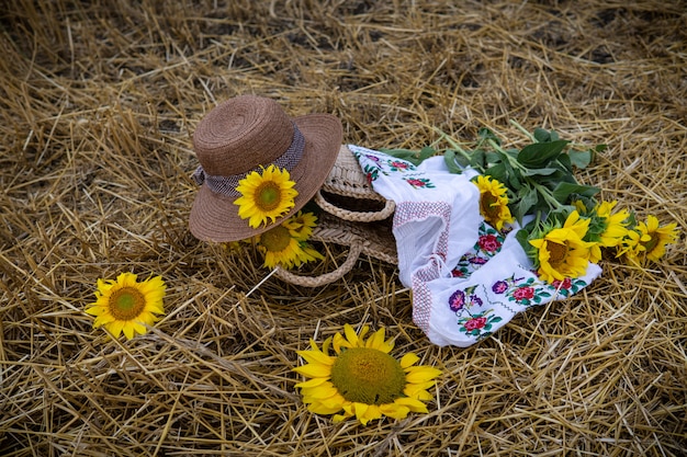 Still life of hats and baskets with sunflowers on a mowed field