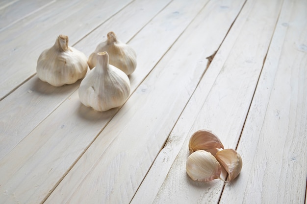 Photo still life of a heads and a cloves of garlic on a white wooden table