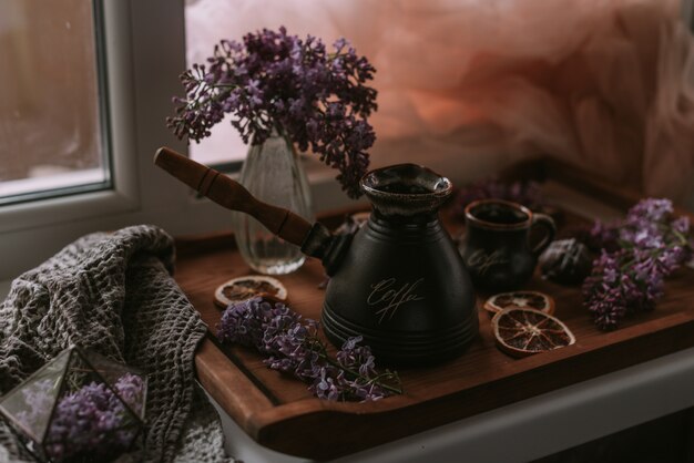 Still life of lilac flowers, coffee and chocolate on wooden tray