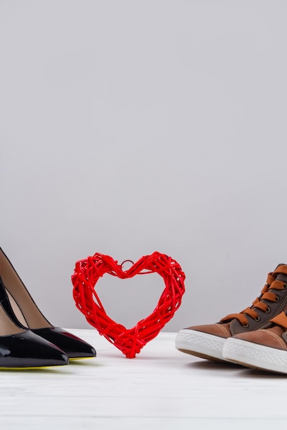 Still life of mens and womens shoes and red heart