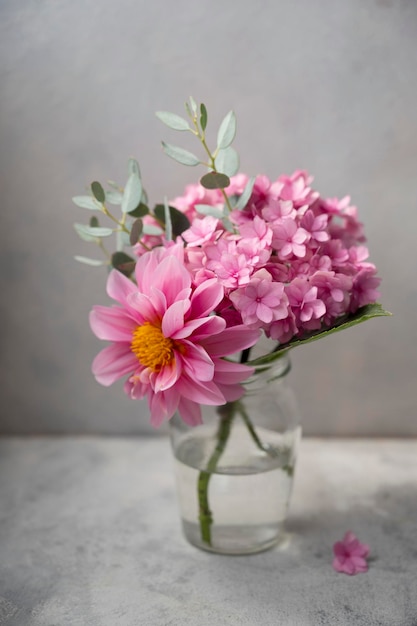 Still life pink flower bouwuet pink hydrangea and dahlias in glass vase on neutral background soft selective focus