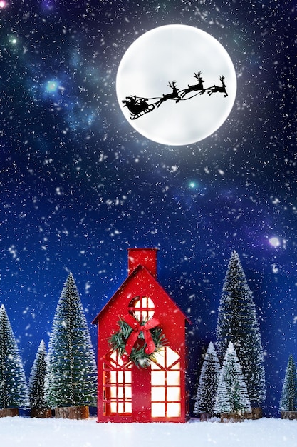 Still life of red Christmas toy house and Santa Clause sleigh over full moon Creative Christmas composition with Santa Clause Christmas background