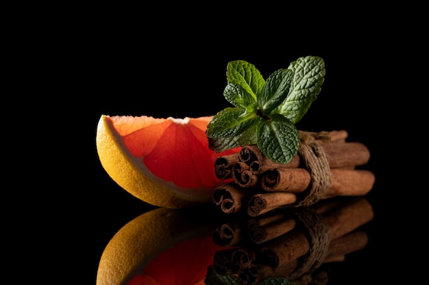 Still life of red orange cinnamon and mint isolated on black background