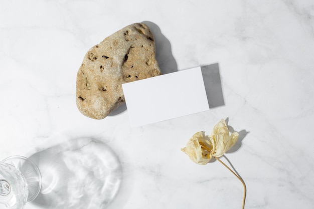 Still life scene with glasses on marble background in sunlight and blank business greeting card invi