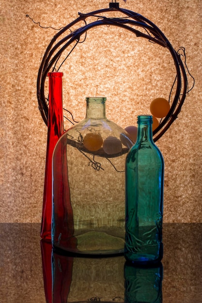 Still life with colored bottles and a vine