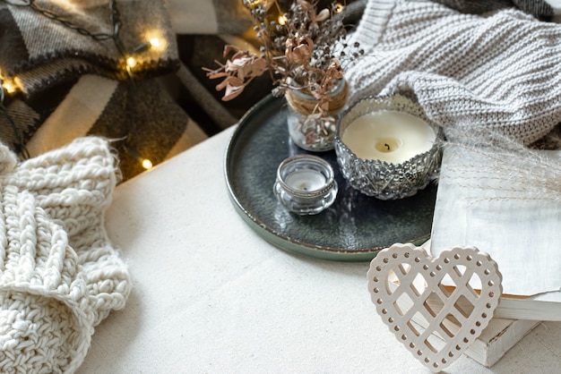 Still life with a decorative heart, books and candles in candlesticks. The concept of Valentine's day and home decor.