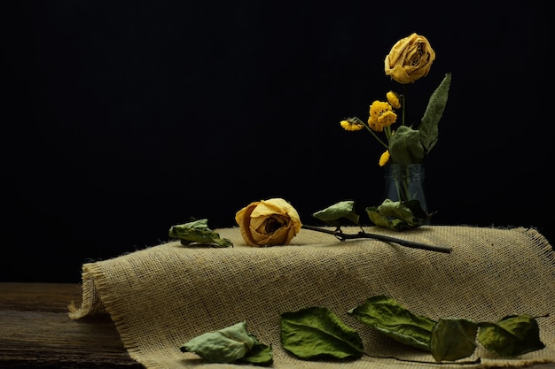 Still life with Dried rose placed on the burlap sack and put in the glass bottle.