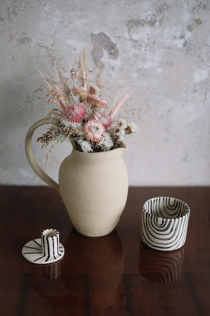 Photo still life with dry flowers in a ceramic vase and a cup home decor interior details