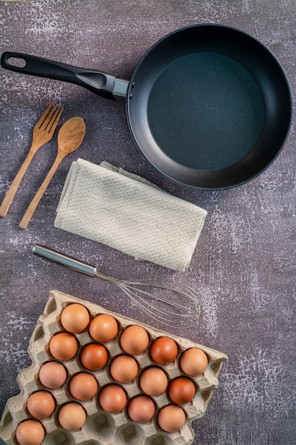 Still life with eggs and pan on wooden table top viewAnimal